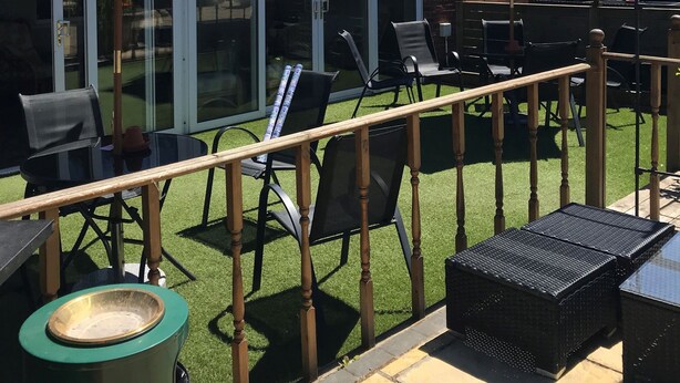 A patio area with outdoor seating, including tables and chairs, and two red umbrellas providing shade. - Black Bull Inn (Immingham)