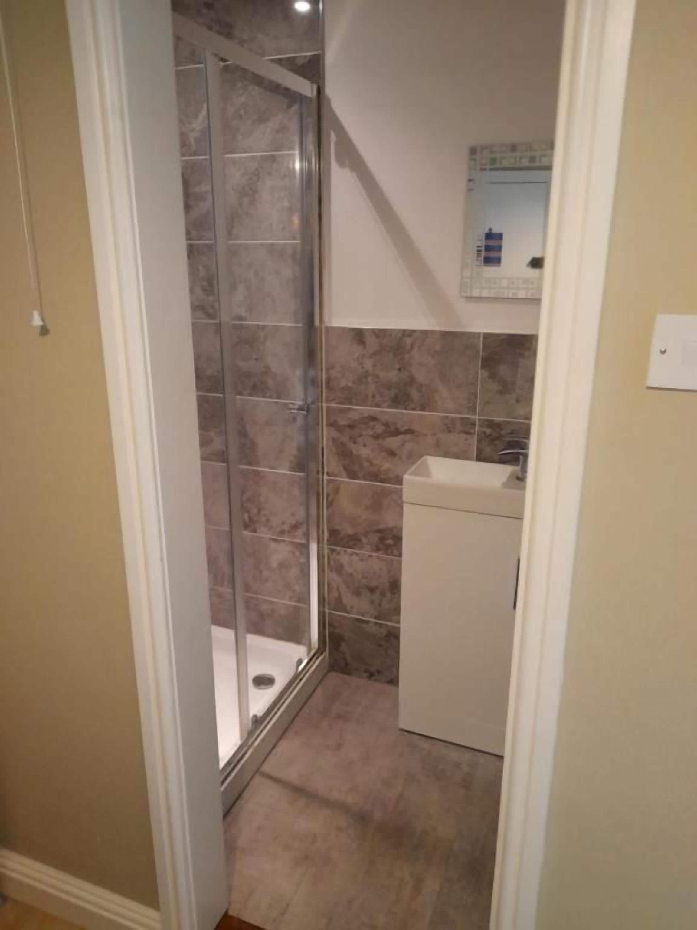 Een badkamer met een douche, wastafel en toilet.