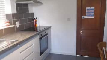 A kitchen with a stove, oven, and a wooden door.