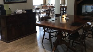A dining area with a large wooden table, chairs, a chandelier, a fireplace, and a painting on the wall. - Black Bull Inn (Immingham)