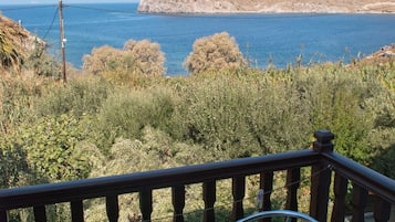 A balcony with a table and chairs overlooking a coastal landscape.