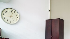 A reception area with a wall-mounted clock, a wooden cabinet, and a white counter.