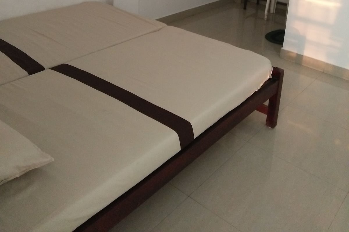 A room with two single beds, a small desk, and a chair.