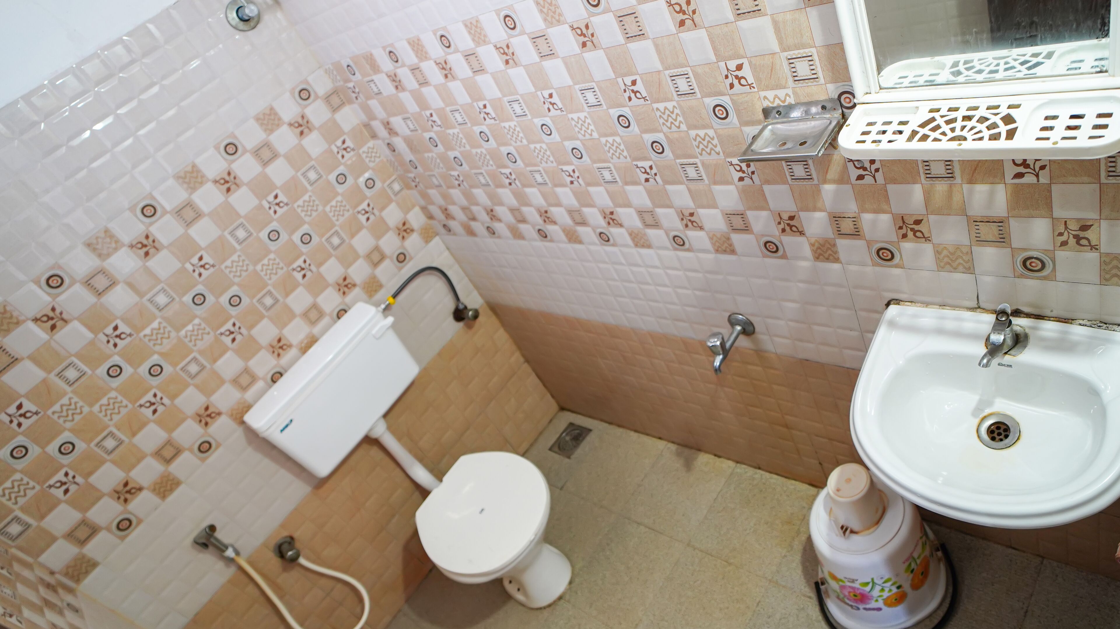 Une salle de bain avec des toilettes, un lavabo et des carreaux décorés.