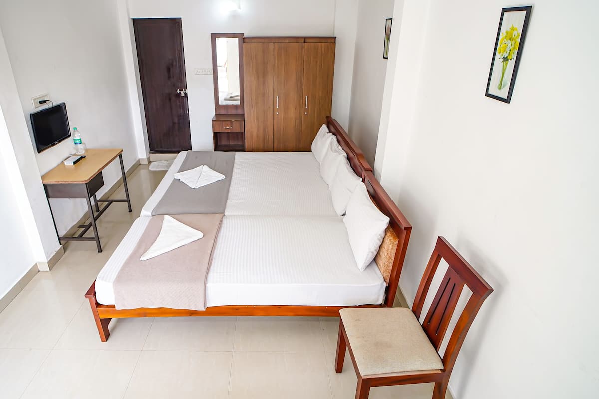 A neatly arranged bedroom with a bed, bedside table, chair, and a wardrobe.