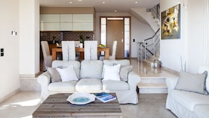 A modern living room with a sofa, coffee table, and a dining area with chairs and a table. - Alivia Lefkas (Lefkada)