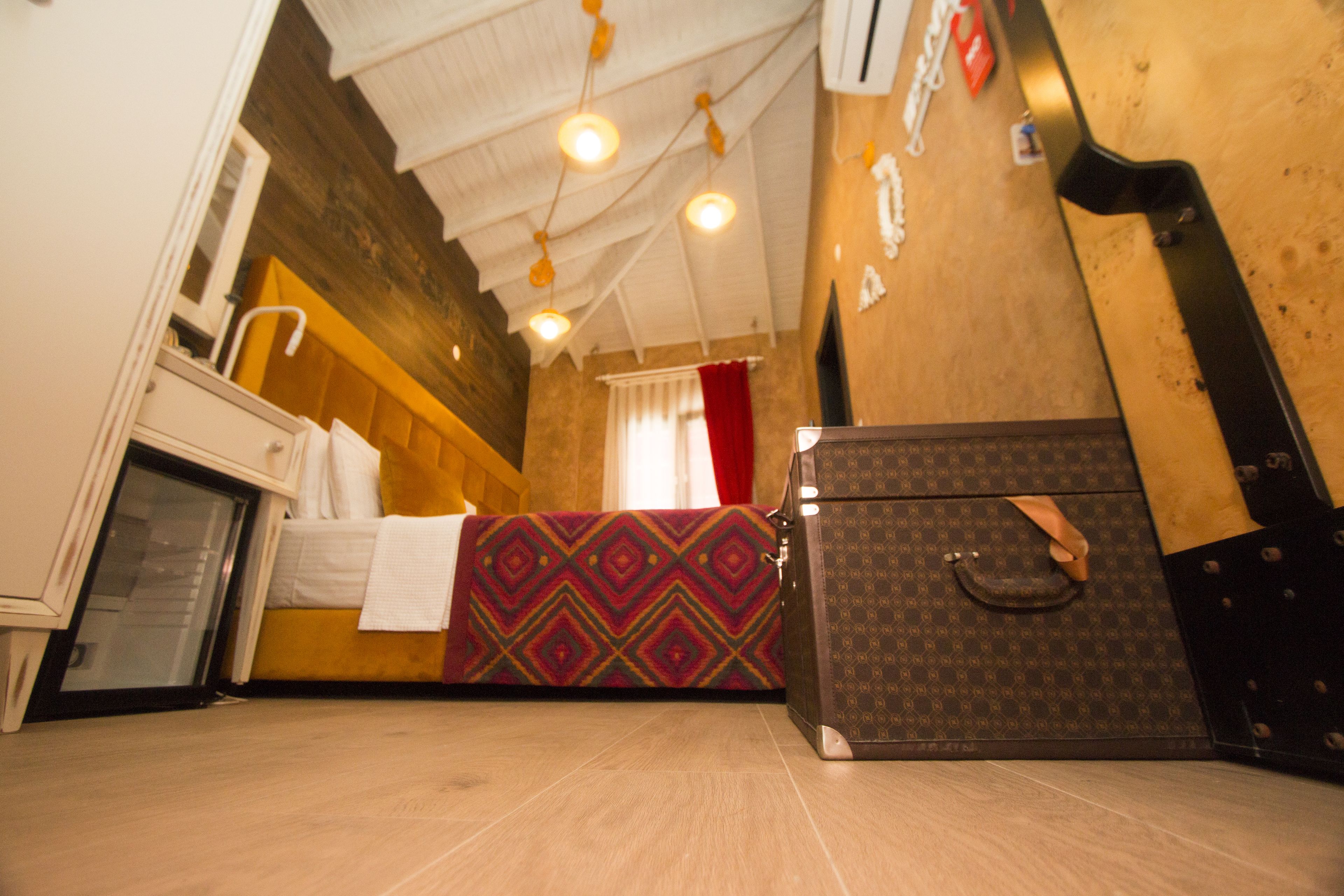 A hotel room with a bed, a suitcase, and a wooden wall.
