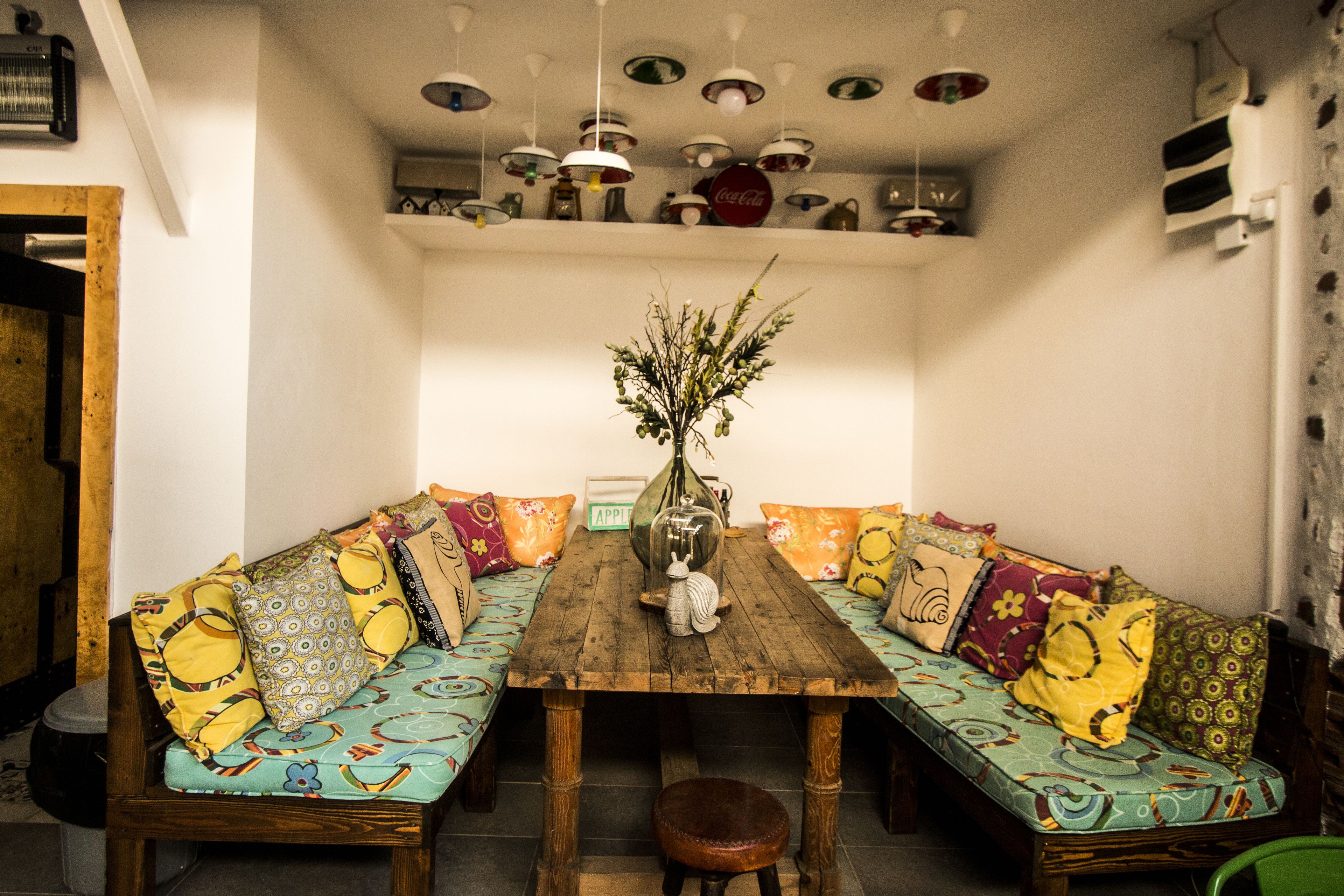 A dining area with a wooden table and two sofas with colorful cushions.