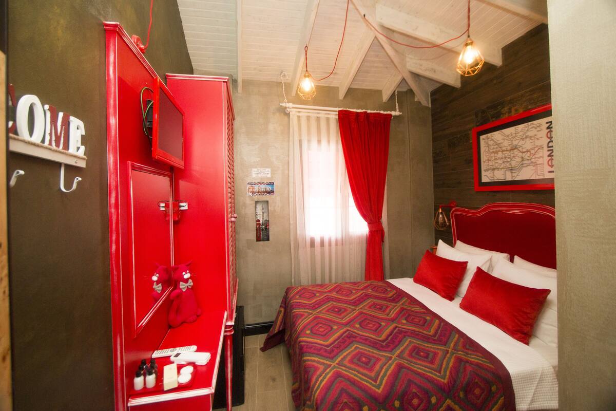 Een slaapkamer met een rode garderobe, een bed met rood-witte beddengoed en een kaart aan de muur.