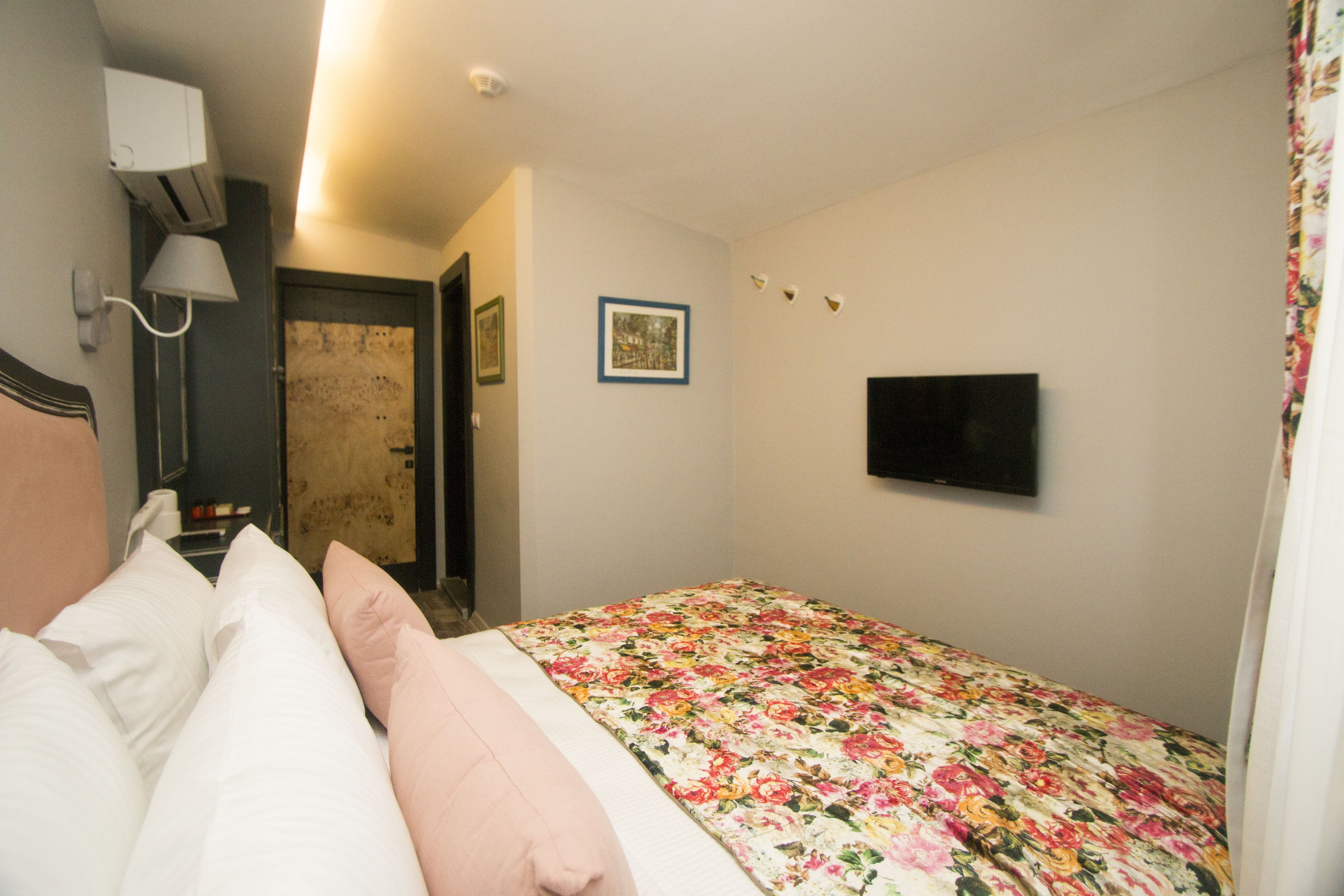 Un dormitorio con cama, televisor, puerta y aire acondicionado instalado en la pared.