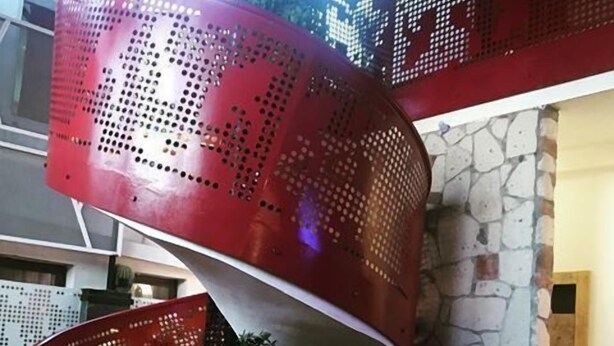 A modern interior with a curved red metal chair, a large terracotta pot, and a small table with a decorative animal figure. - Incitta Otel (Seferihisar)
