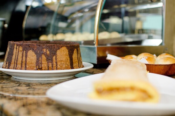 A dessert display with a chocolate cake and a rolled pastry on a marble countertop.
