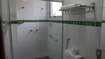 A shower area with a glass door, a towel rack, and a toilet with a towel.