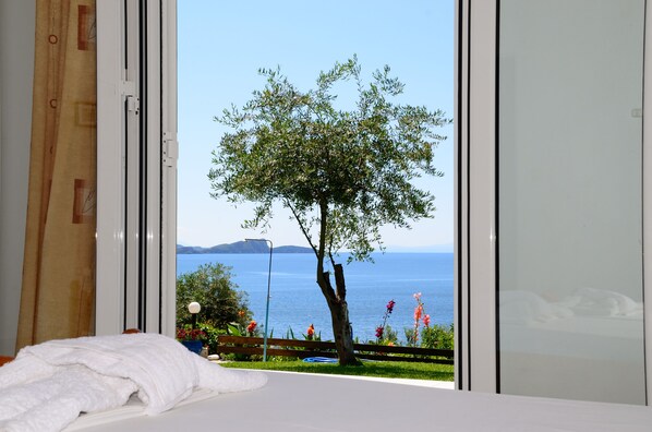 Ein Schlafzimmer mit Meerblick, einem Baum und einem Balkon mit Blumen.