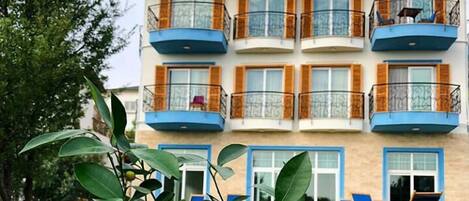 A multi-story hotel with balconies, a lawn, and outdoor seating.
