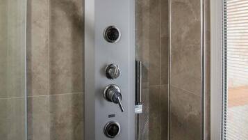 Une douche moderne dotée d’un pommeau de douche à pluie, de plusieurs robinets de réglage et d’un pommeau de douche à main.