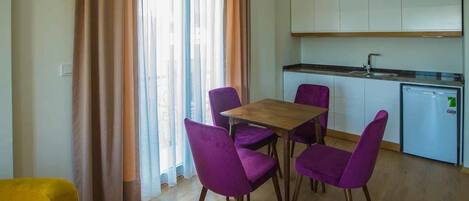 A compact kitchen with white cabinets and a small refrigerator.