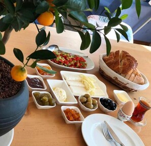 A table set with various food items including bread, cheese, olives, and a fruit tree with oranges.