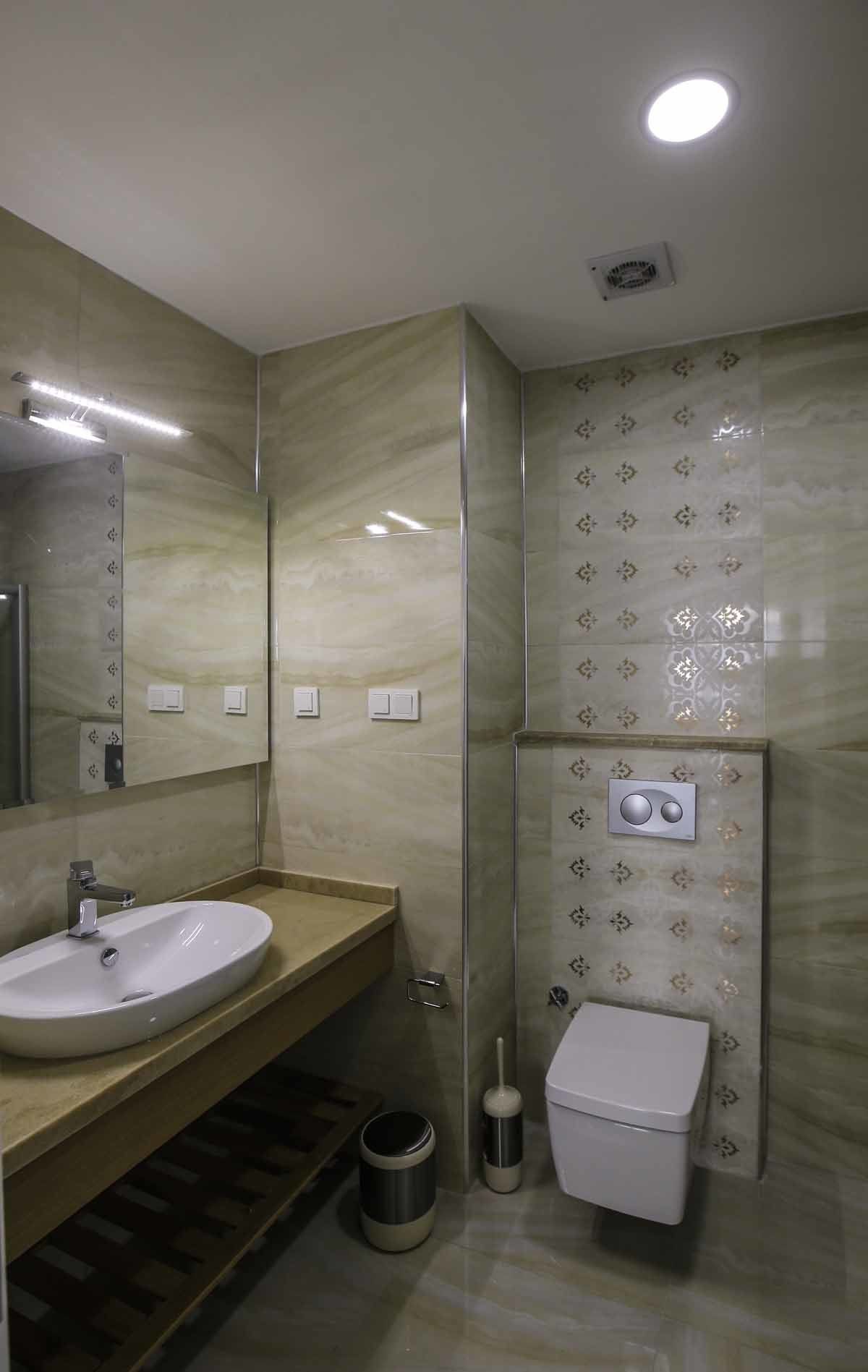 A modern bathroom with a large mirror, a sink, a toilet, and a shower area.