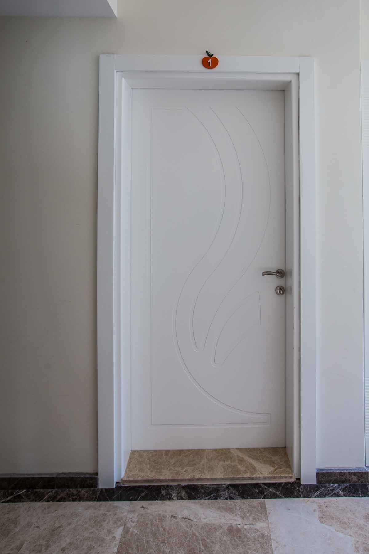 A white door with a circular design and a small orange sign above it.