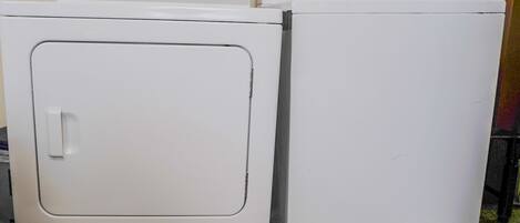 Two white Whirlpool washers side by side in a laundry room with a metal rod above them.