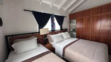A double bed with a wooden headboard, a bedside table with a lamp, and a wardrobe with a microwave.