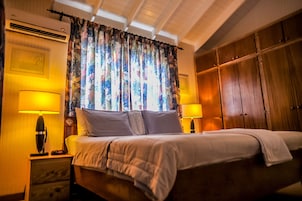 Habitación de hotel con cama, dos lámparas de noche, un armario de madera y una cortina estampada.