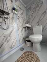 A bathroom with a toilet, a sink, a shower, and a mirror.