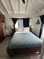 A bedroom with a bed, nightstands, a dresser, a window with curtains, and a ceiling fan.