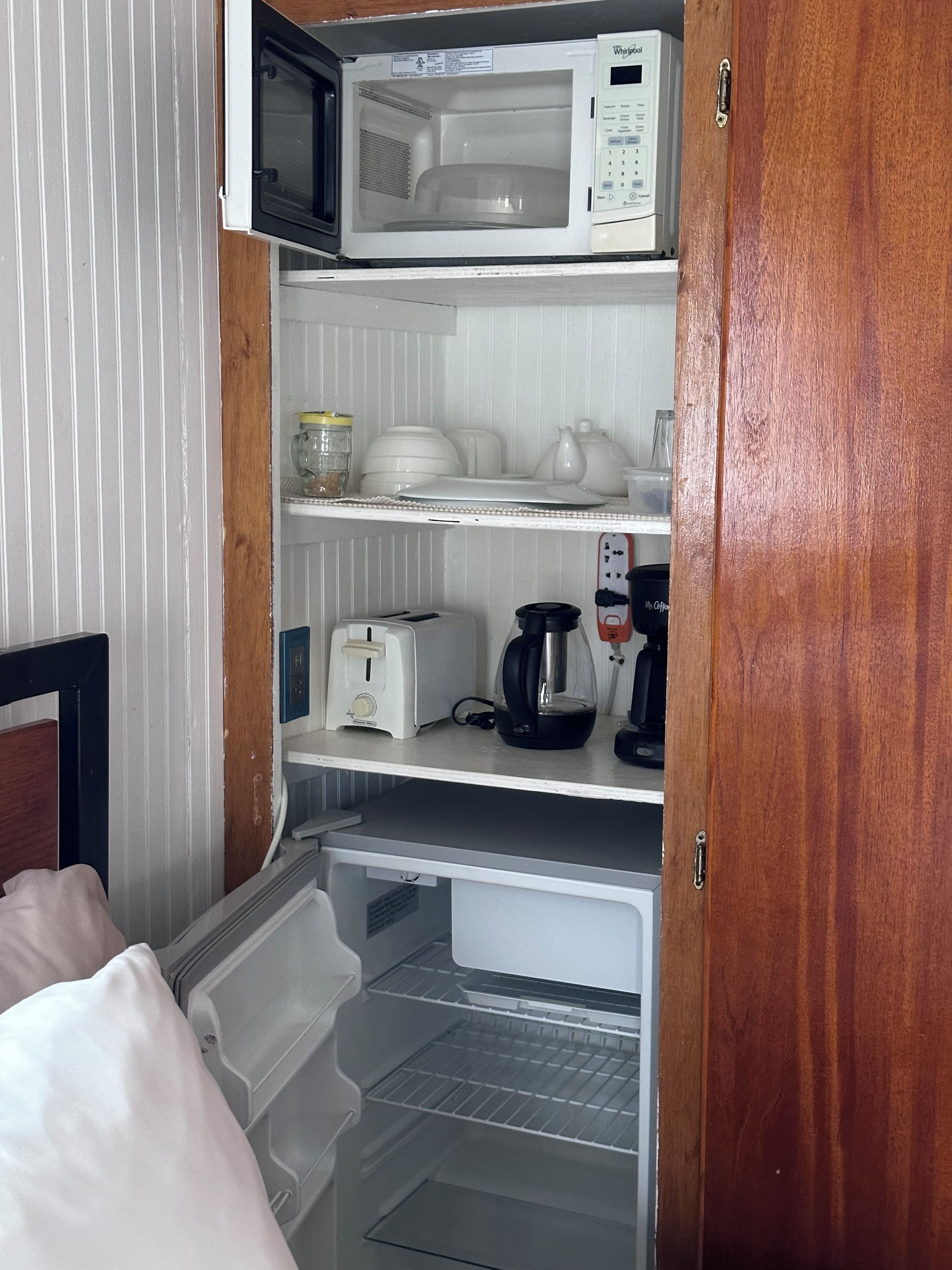 Una kitchenette compacta equipada con microondas, tostadora, hervidor y cafetera.