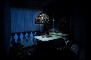Un balcón tenuemente iluminado con una mesa, sillas y una lámpara decorativa.