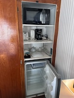 Cocina compacta equipada con microondas, cafetera, hervidor y refrigerador con congelador.