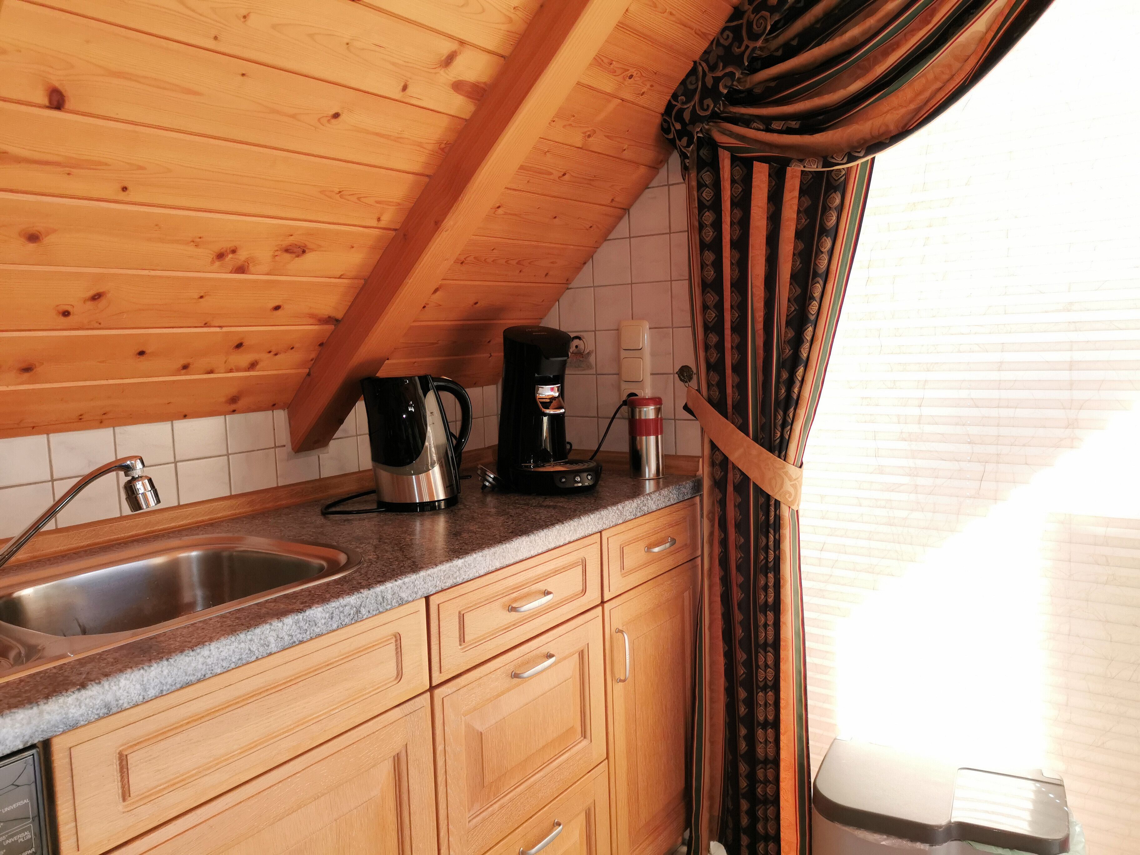 A kitchen with wooden cabinets, a granite countertop, a coffee maker, and a kettle.