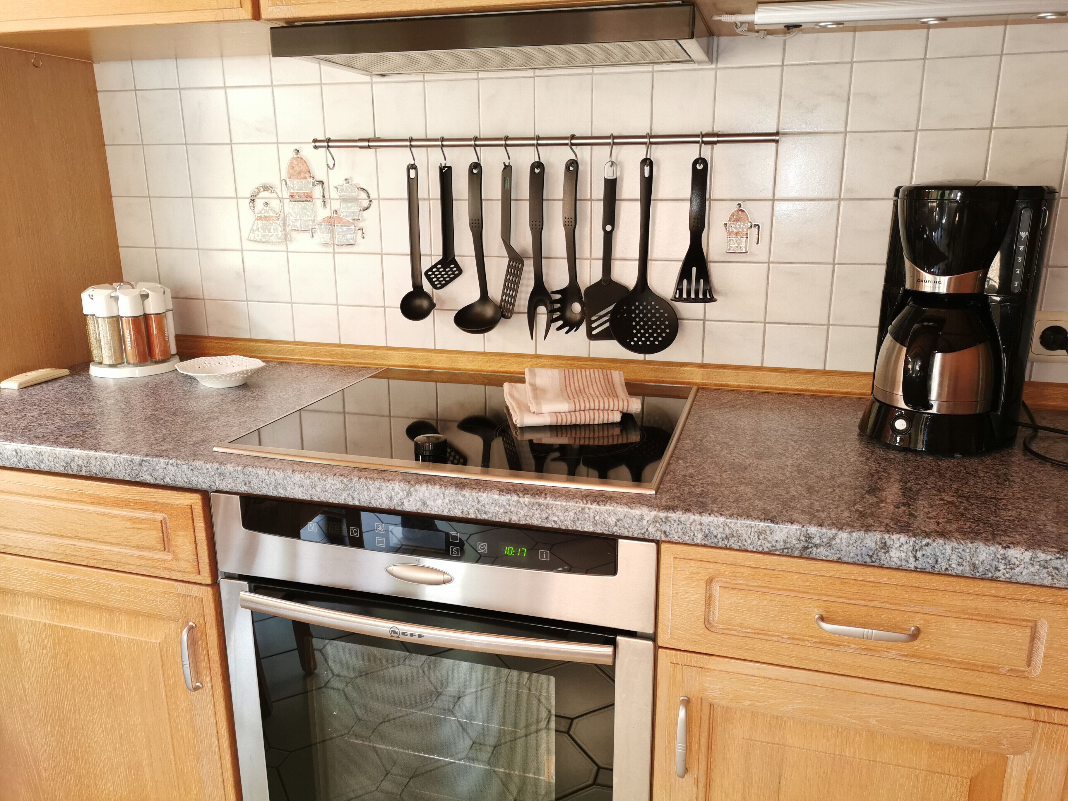 Eine Küche mit einem Edelstahl-Geschirrspüler, einer Kaffeemaschine und verschiedenen Küchenutensilien, die an der Wand hängen.