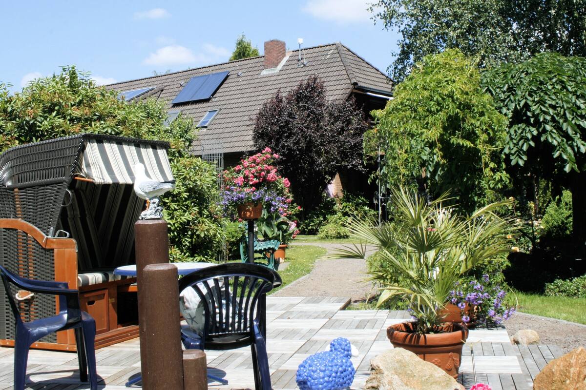 Eine Terrasse mit Gartenmöbeln, ein Garten mit Blumentöpfen und ein Haus mit Solaranlage.
