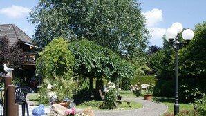 Un sentier de jardin bordé de plantes en pot, un banc et un belvédère.