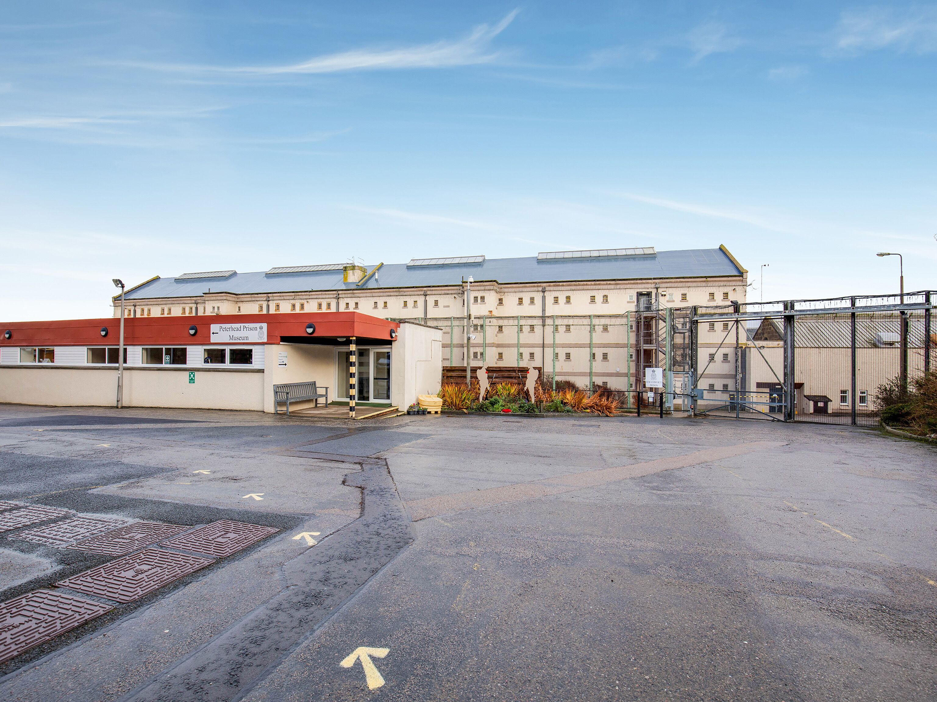 Un edificio con techo rojo y un letrero que dice "Peterhead Prison Museum".