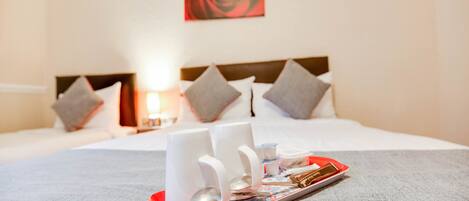 A neatly made bed with pillows, a tray with a cup and a spoon, and a red and white tray.