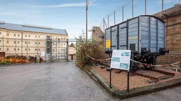 Un andén ferroviario con un tren de carga, un edificio grande y un cartel.