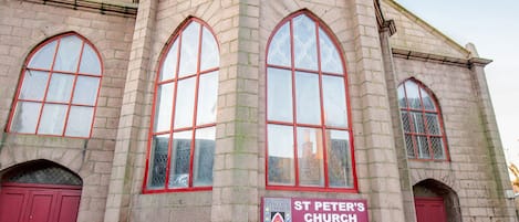 A historic church building with large arched windows and a prominent red door.