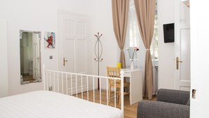 A bedroom with a bed, a desk, a chair, and a TV.