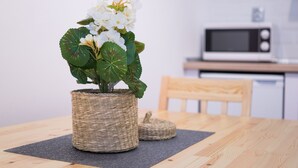 A dining table with a woven basket containing white flowers, a dark placemat, and a wooden chair.