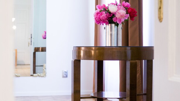 A wooden floor with a table and a vase of flowers.