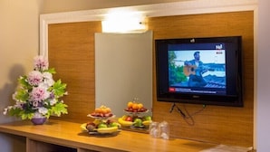 A reception desk with a television displaying a news program, a floral arrangement, and fruit trays. - Grand Rosa Hotel (Istanbul)