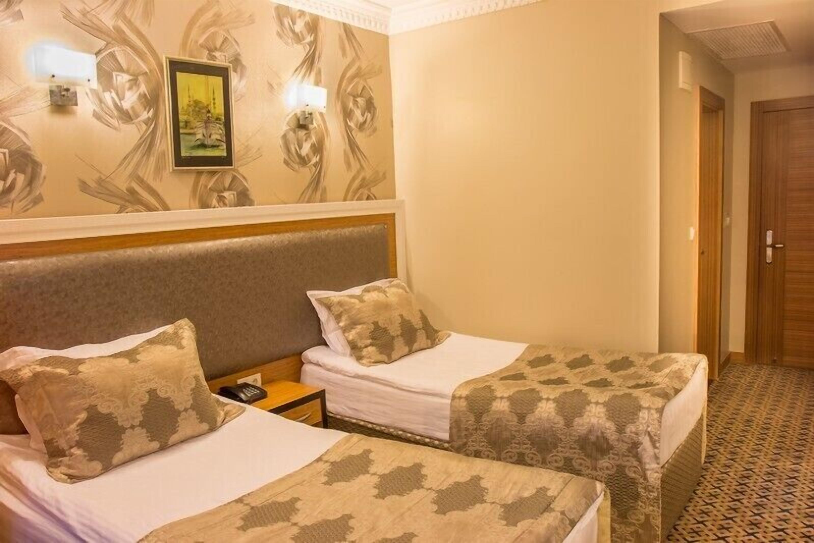 A hotel room with two beds, a nightstand, a framed picture on the wall, and a patterned floor.