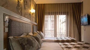 A hotel room with two beds, a television, and a view of the city through large windows. - Grand Rosa Hotel (Istanbul)