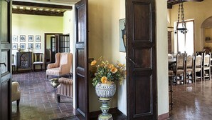 Una habitación espaciosa con un gran puerta de madera, una planta en maceta y una silla.