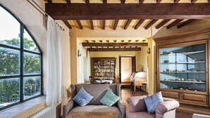 Una sala de estar acogedora con techo de madera, un ventanal grande, una chimenea y una estantería.