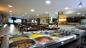 Un buffet proposant une variété de plats et un espace repas avec des tables et des chaises.