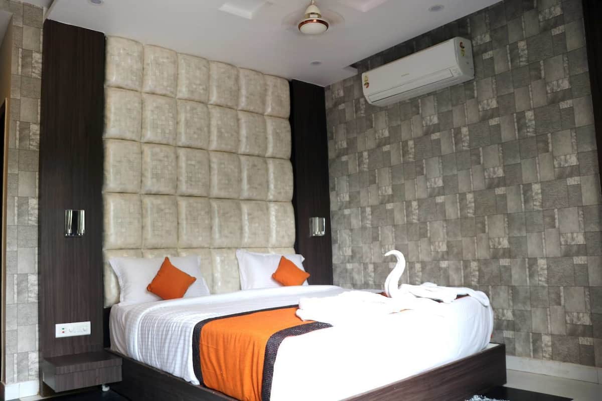 A modern hotel room with a large bed, two pillows, a swan decoration, and an air conditioning unit on the wall.